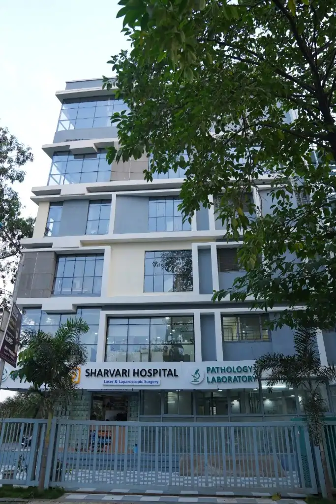 Exterior view of the modern Sharvari Hospital building in Pune, featuring the main entrance, pathology laboratory sign, and glass facade.